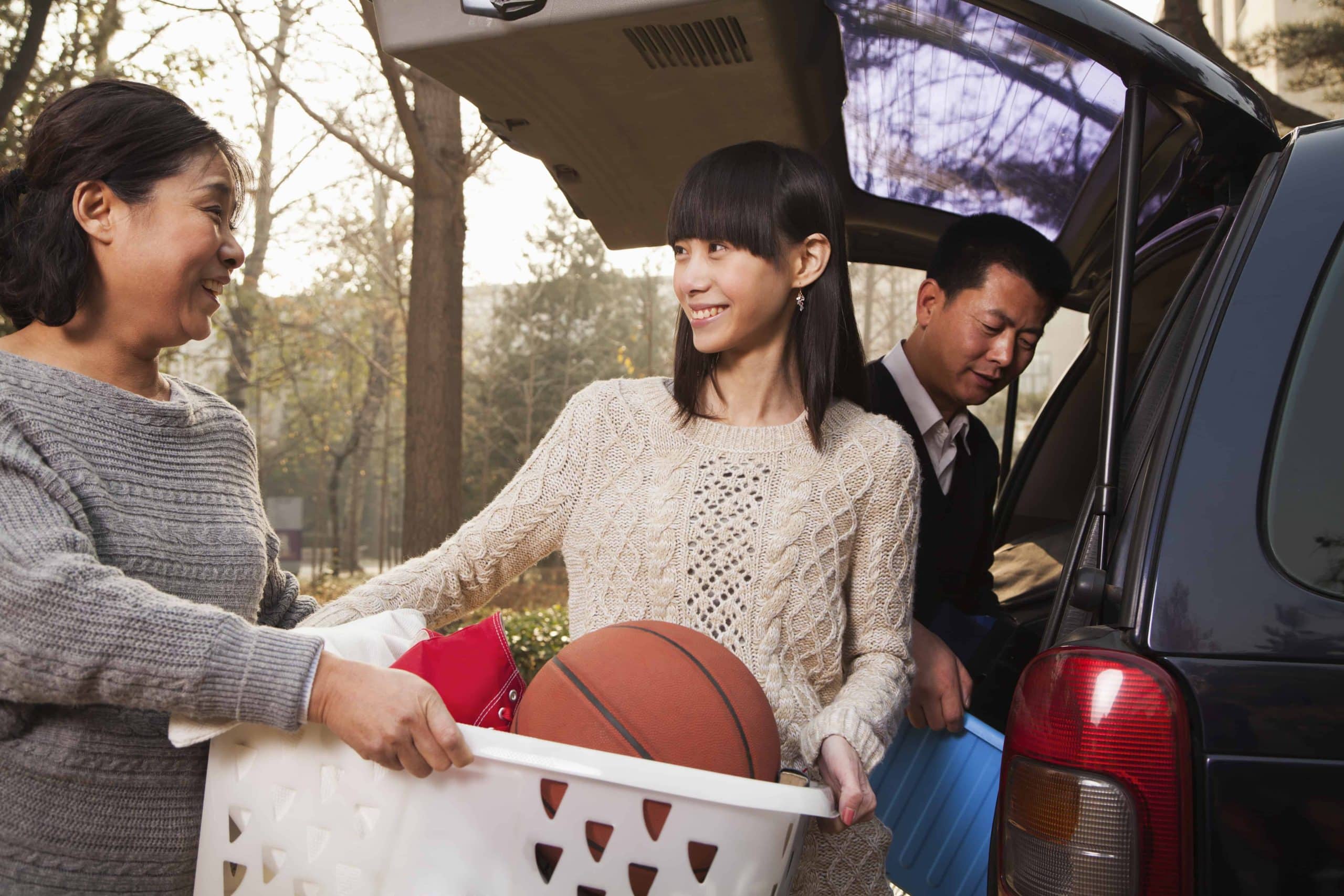Mother and father helping daughter unpack car for college