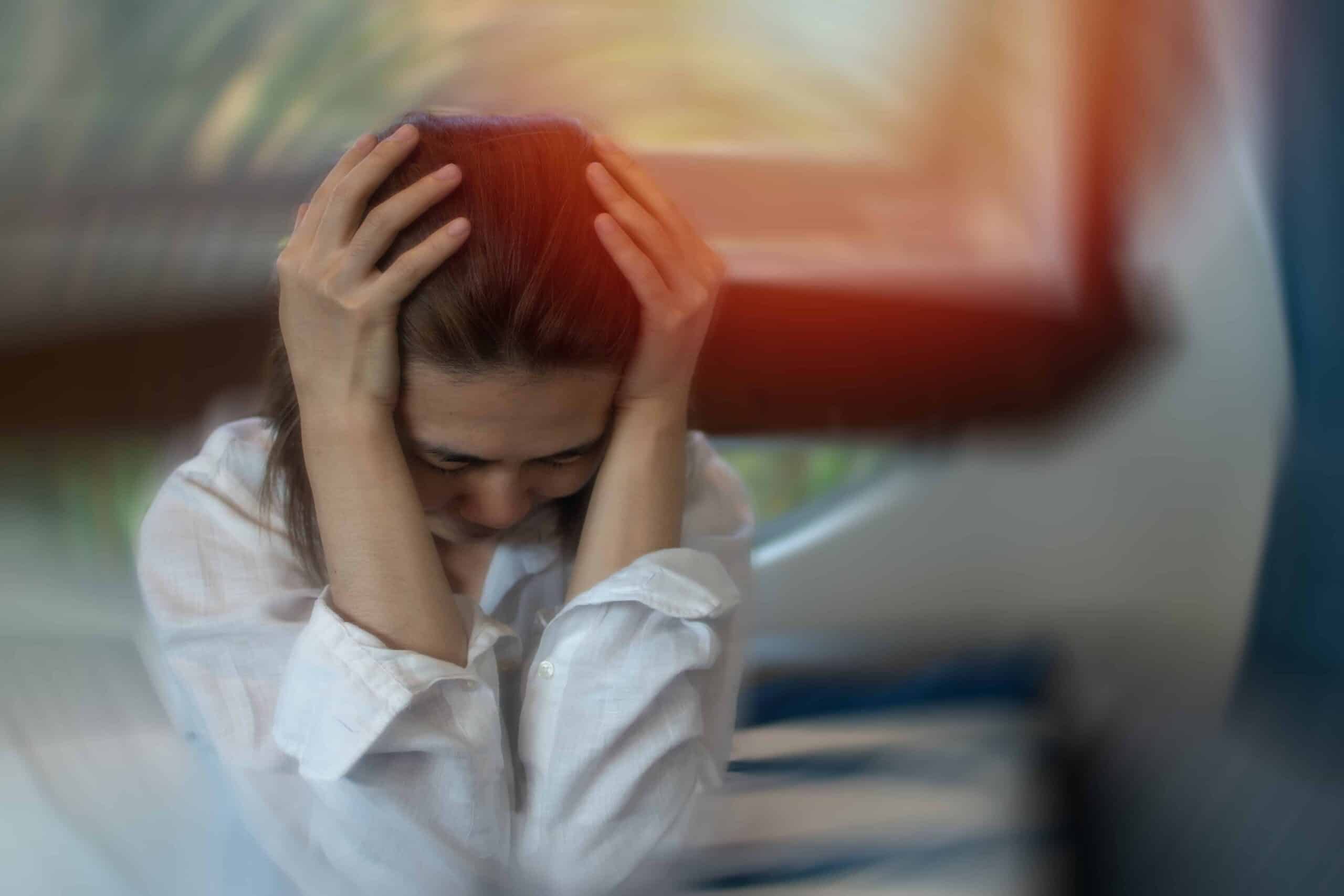 Close-up of a woman with her hands on her head, showing signs of anxiety