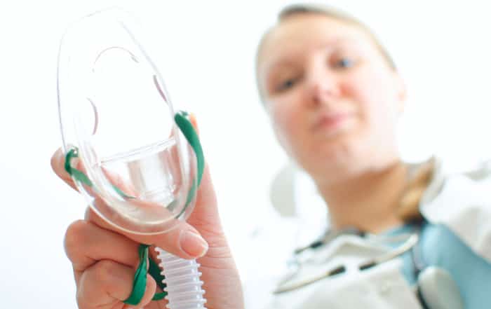 Female assisitant giving gas mask to patient