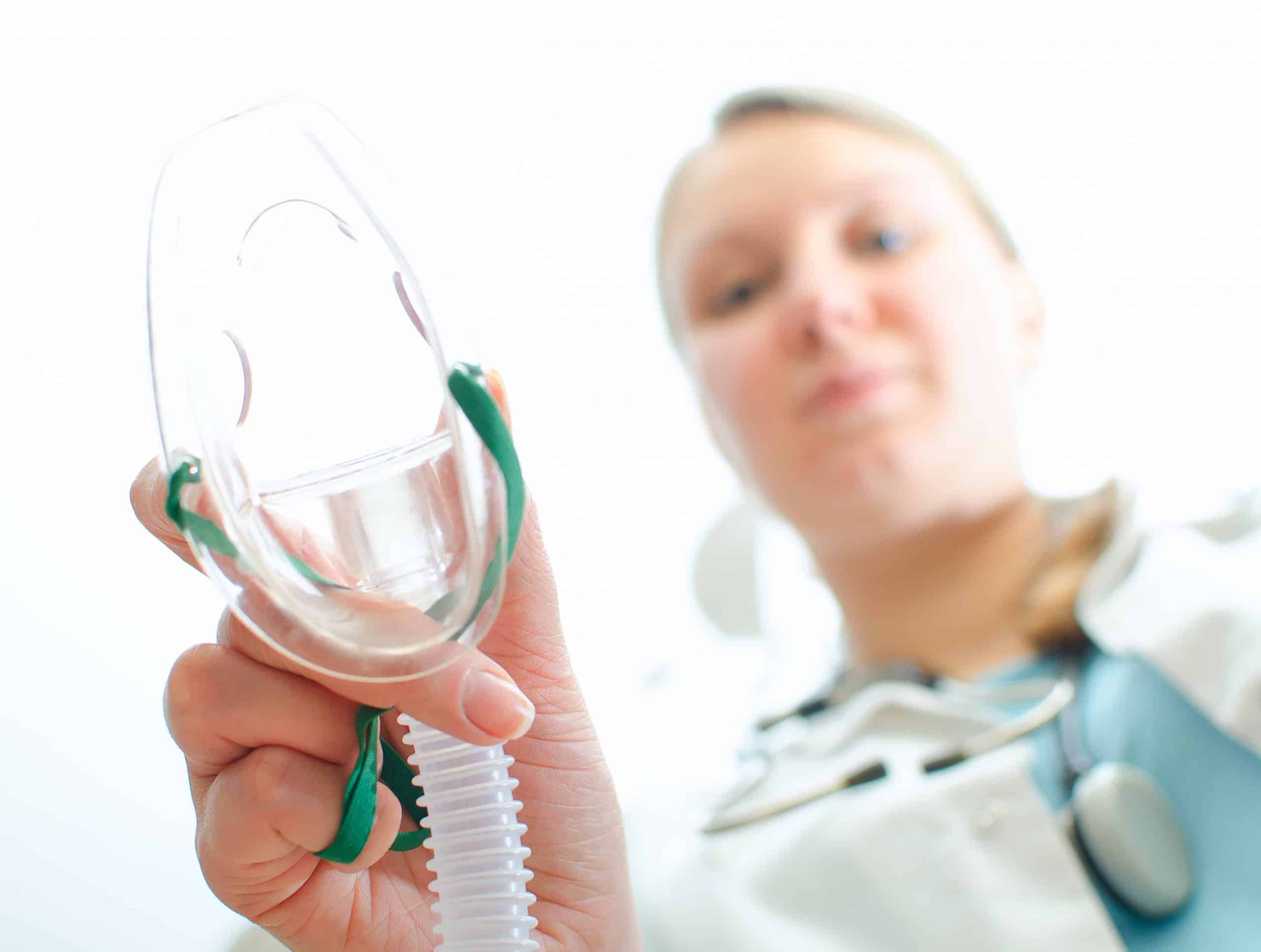 Female assisitant giving gas mask to patient