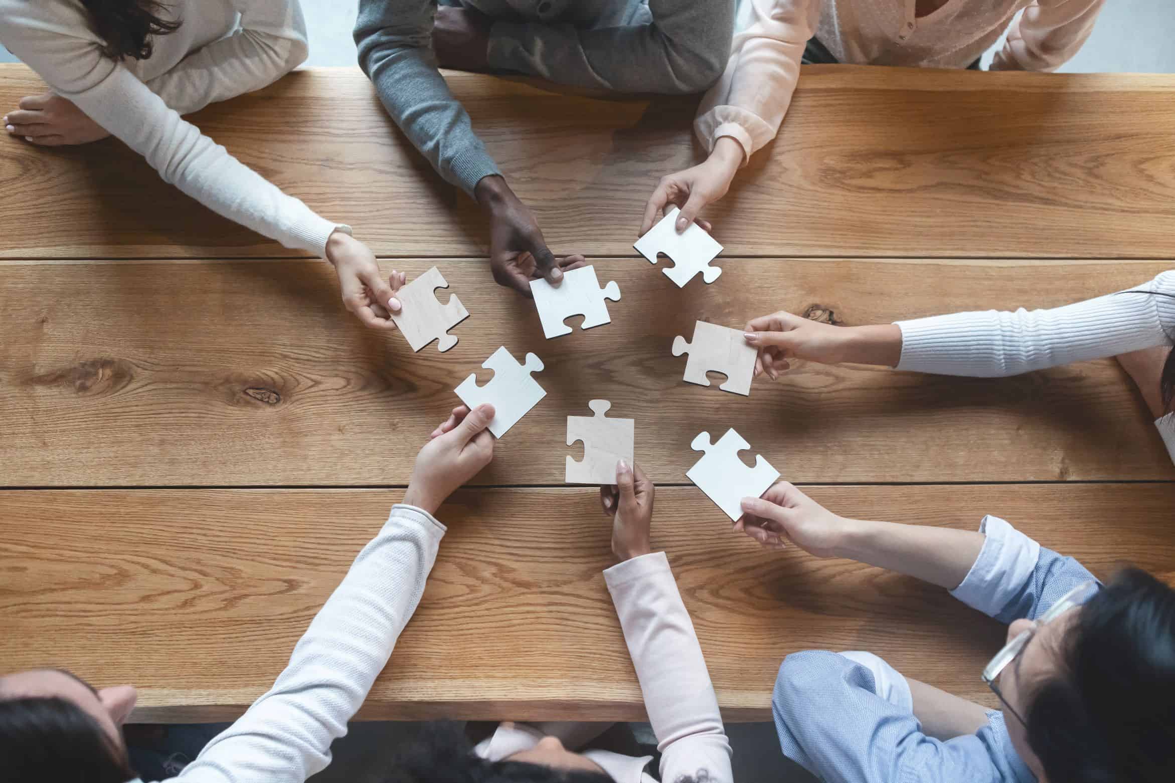 Close-up of a group of people holding puzzle pieces in their hands
