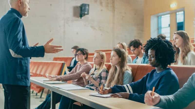 Professor and a group of young students engaged in a classroom discussion