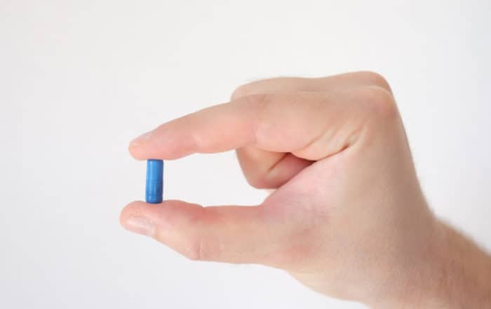 Close-up of a pill between two fingers