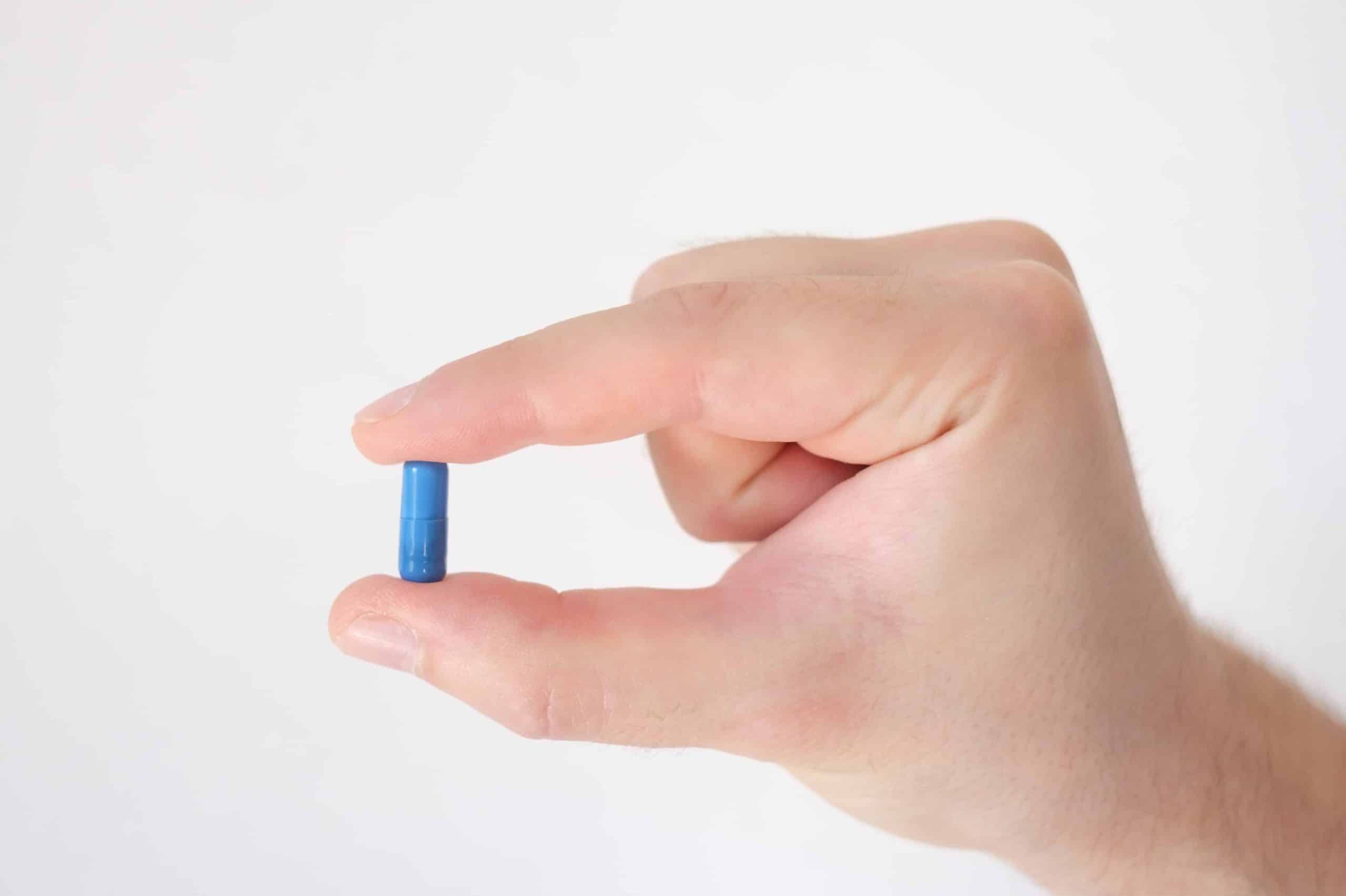 Close-up of a pill between two fingers