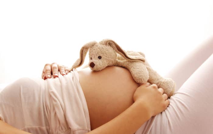 a pregnant woman with a bunny toy on the belly