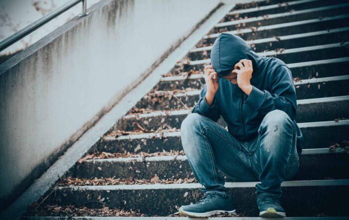 Sad man sitting alone on the stairs in the street