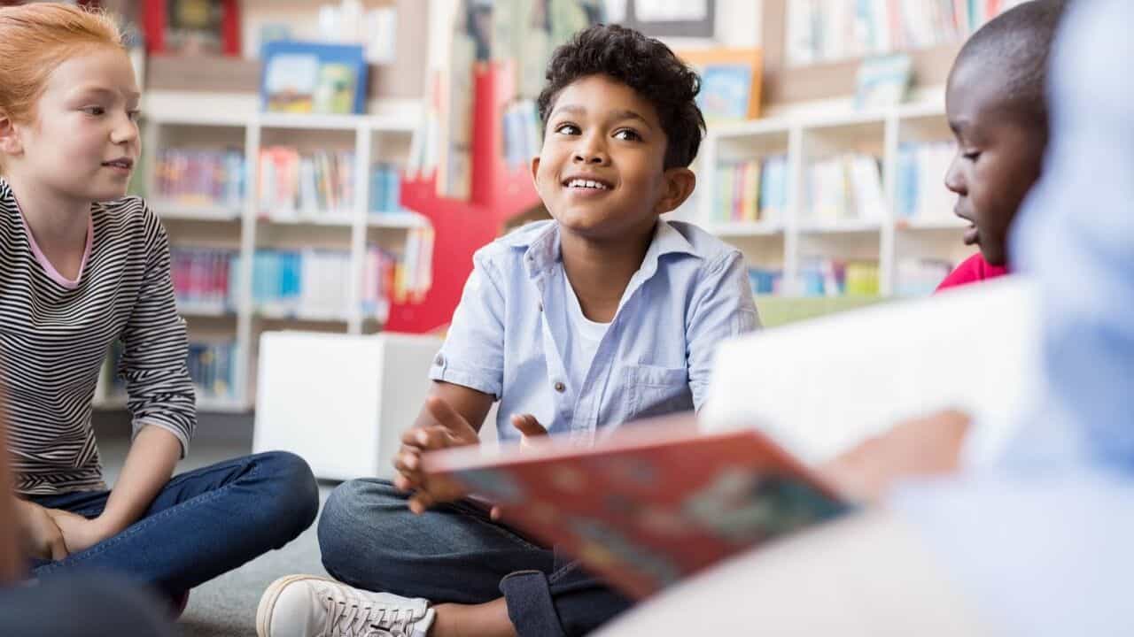 Group of children sitting on the floor in a library, chatting