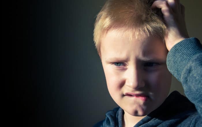 Young kid with a focused expression, biting his lips