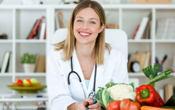Medical professional with a smile, vegetables placed in front