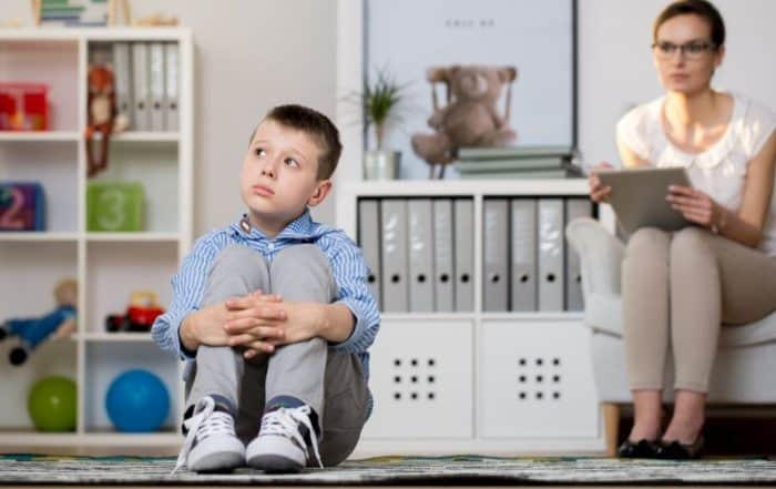 Young child sitting quietly on the floor during a therapy session