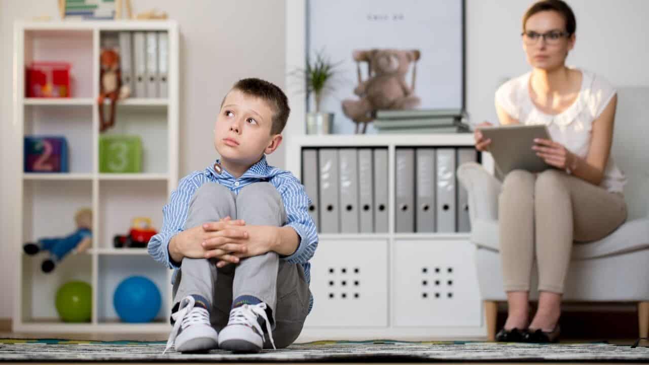 Young child sitting quietly on the floor during a therapy session