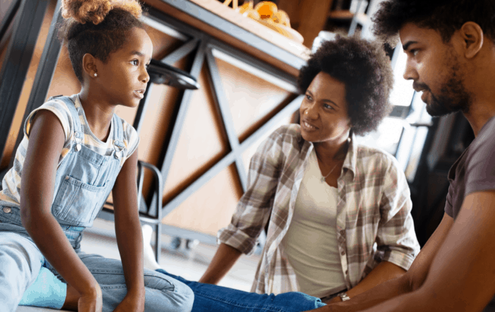 Child talking with parents while sitting on the kitchen floor