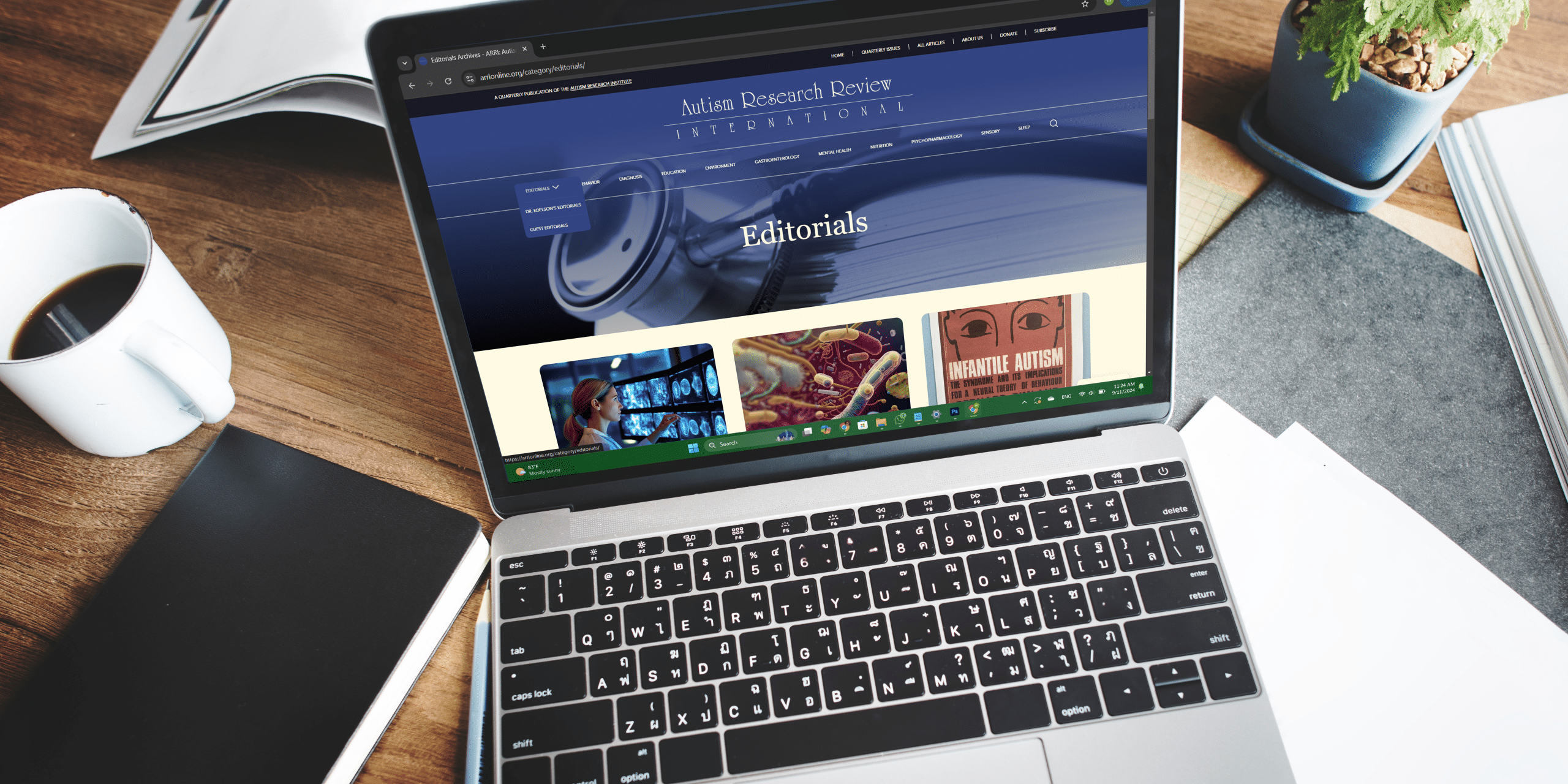 Work desk setup featuring a laptop, coffee cup, notebook, and potted plant